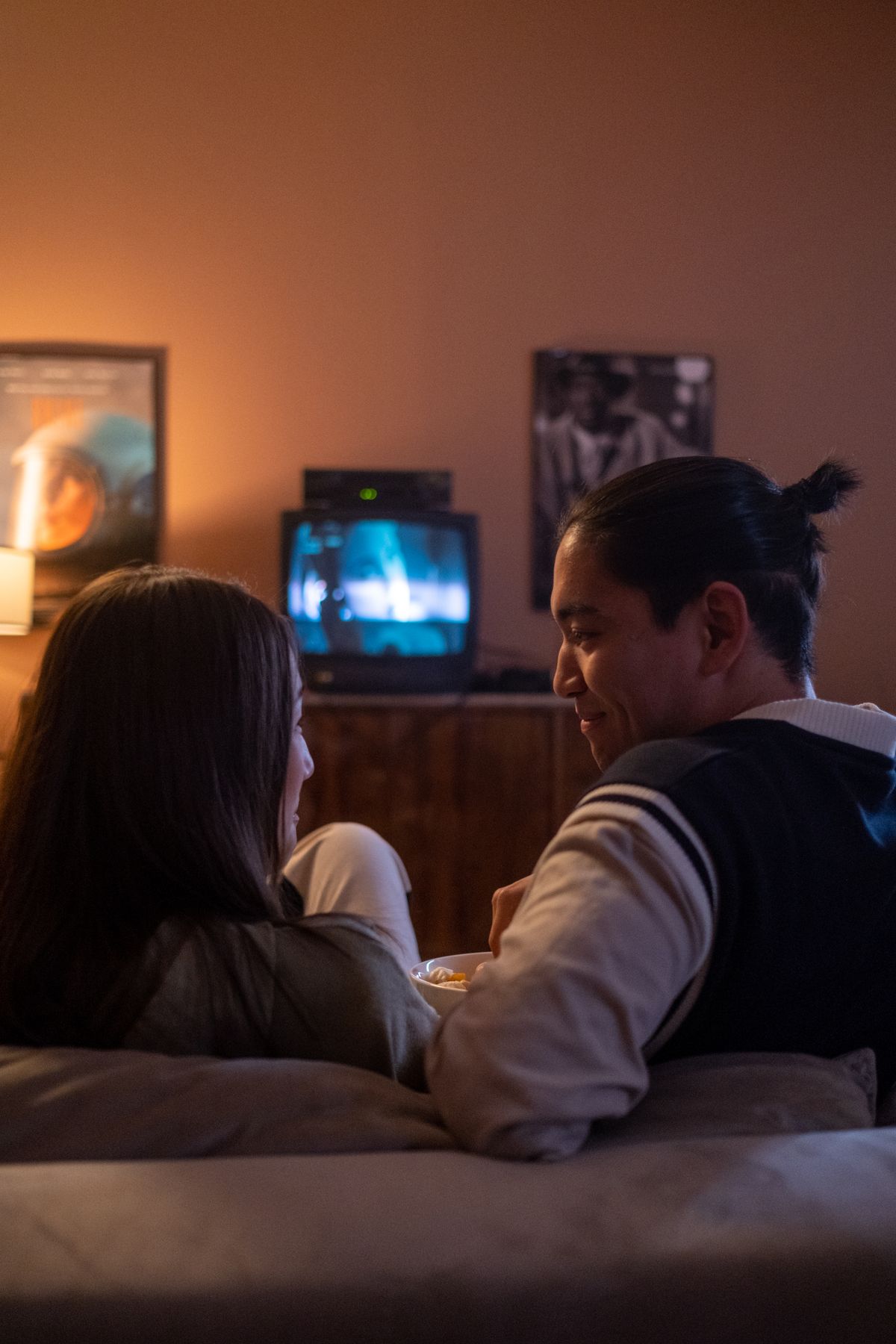 A couple watching TV together on a couch in dim lighting