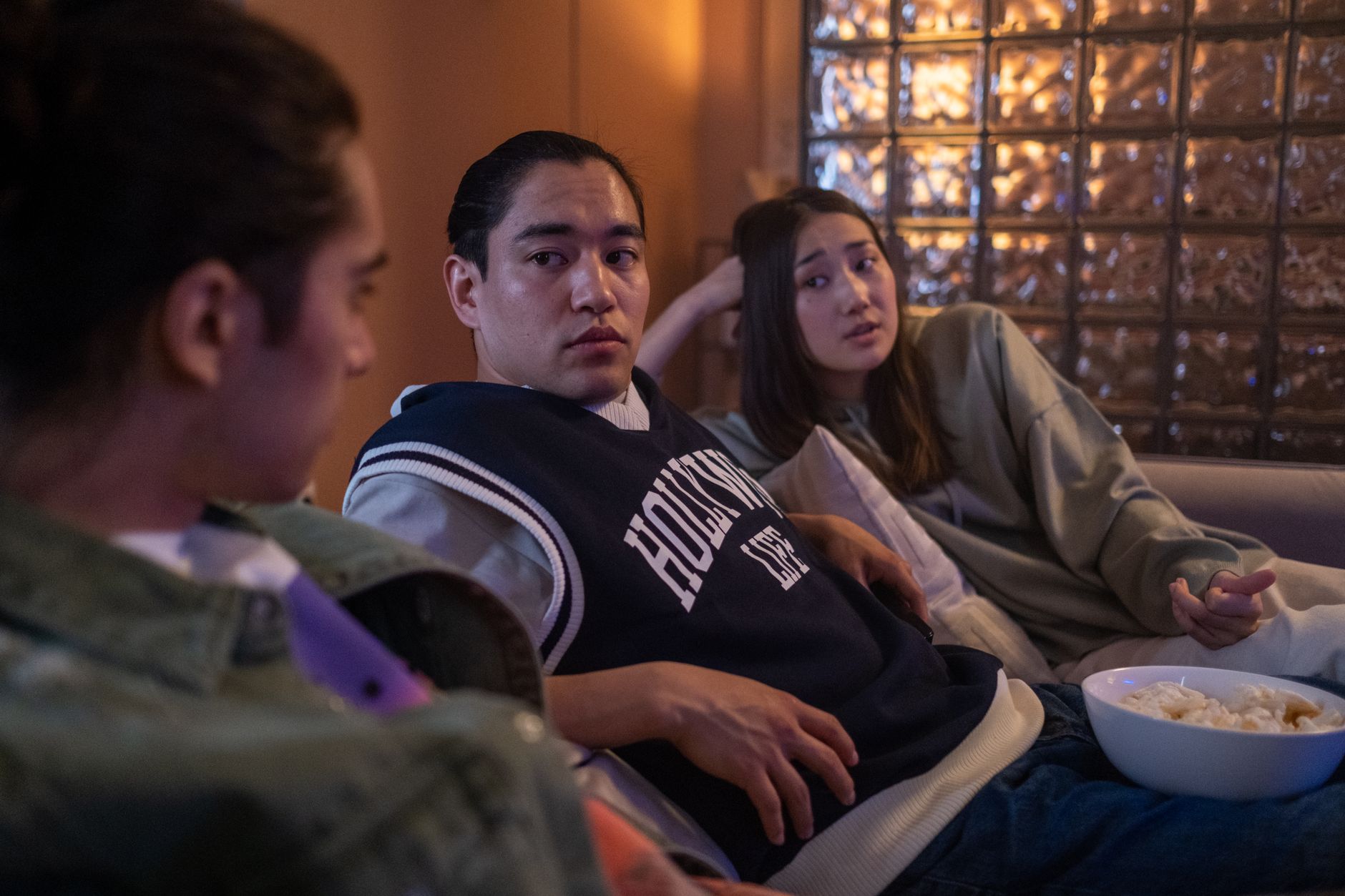 Three friends enjoying a relaxed movie night at home with popcorn and cozy atmosphere.