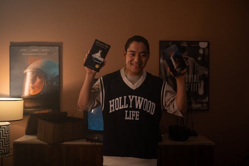 Man holding 2 different films on vhs videotapes.