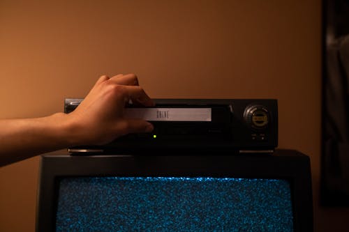 Free Person inserting a videotape into the video player Stock Photo