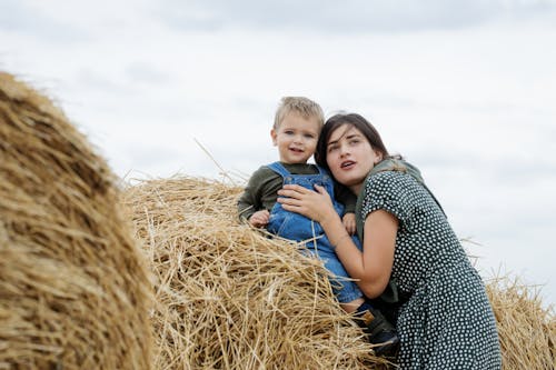 Mother Embracing a Little Boy Sitting on the Haystack