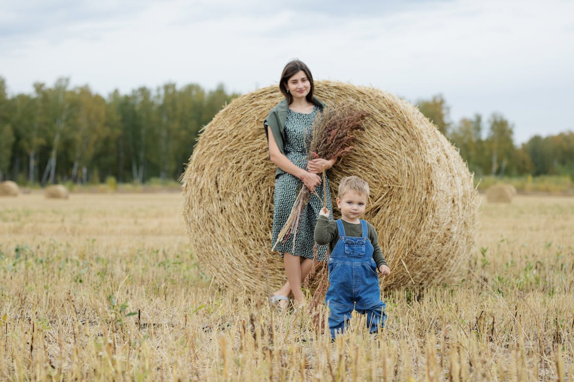 Woman and Child Standing Near the Hay Roll