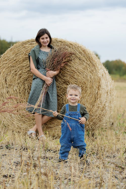 A Boy and a Woman Leaning on a Haystack