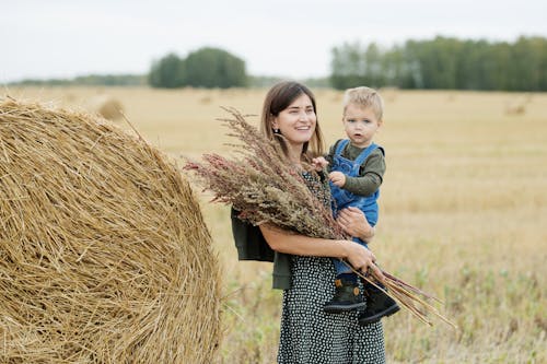 Free Girl in Blue Jacket Sitting on Brown Hay Stock Photo