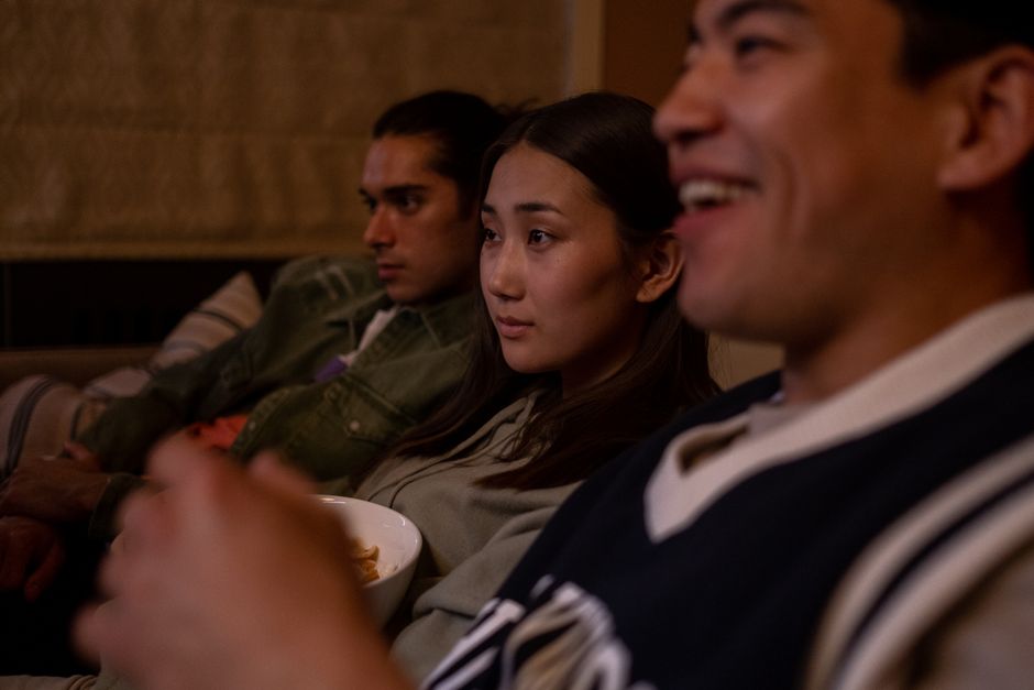 Group of friends relaxing and watching a movie at home, enjoying snacks and laughter.