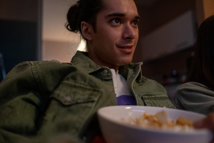 Young Man Eating Snacks And Watching TV