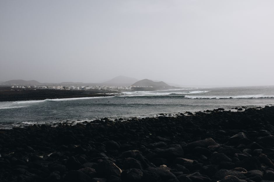A serene coastal view with waves crashing on rocky shores under an overcast sky.