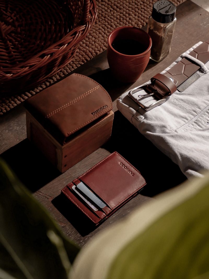 Leather wallet belt and essentials on wooden table