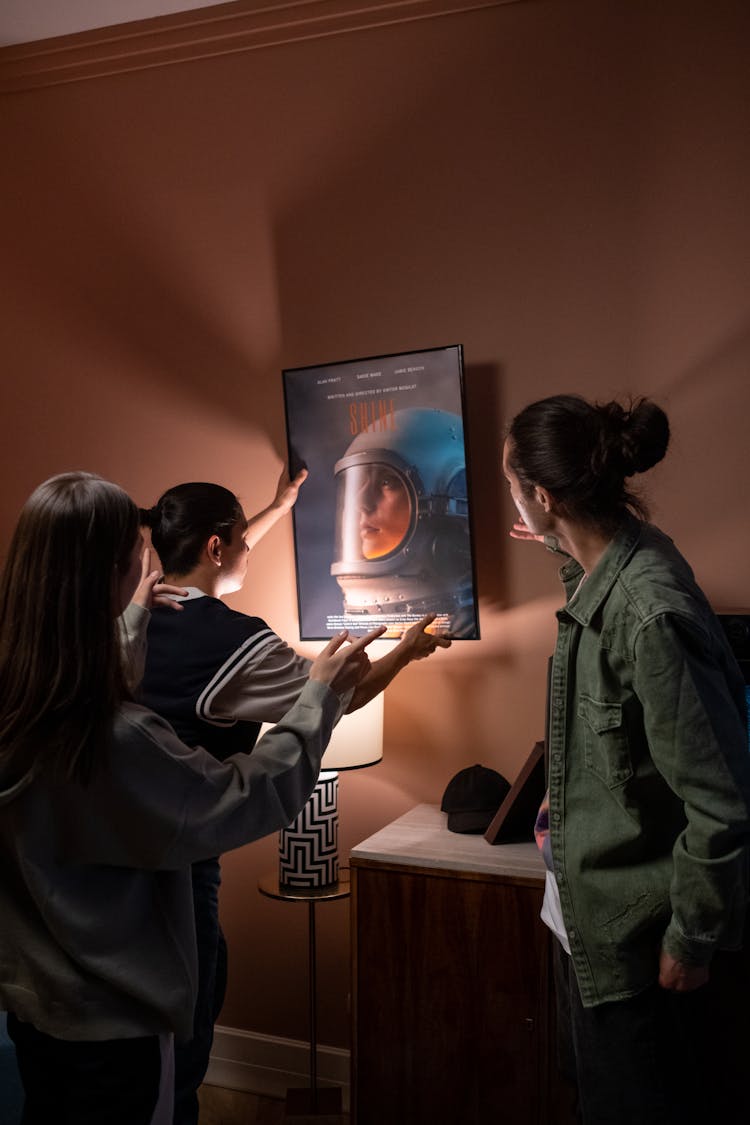 Three Friends Hanging Poster On Wall