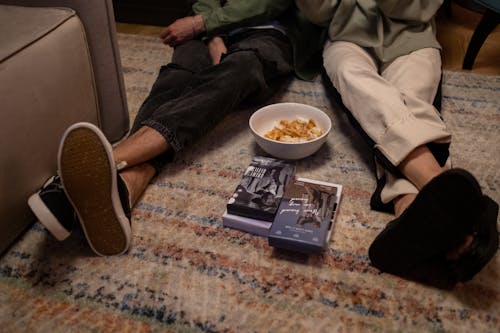 Human legs on floor with movies and snacks