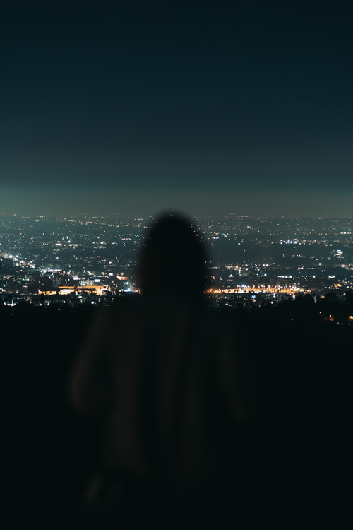 Free Silhouette overlooking illuminated Los Angeles skyline from Griffith Park at night. Stock Photo