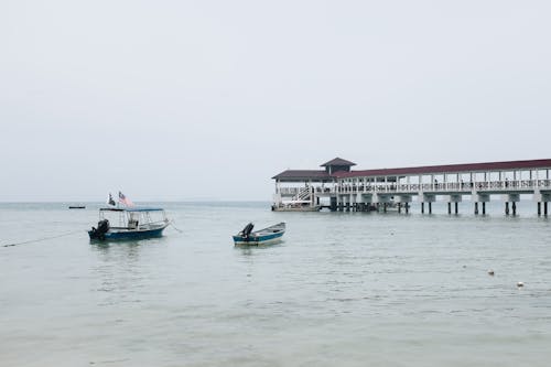 Barco Blanco Y Azul En Cuerpo De Agua Cerca Del Muelle