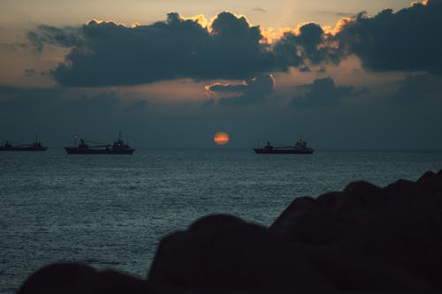 Silhouettes of Ships on an Ocean During Sunset