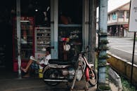 在马来西亚贝苏特，一名男子坐在一家店面旁，骑着摩托车，反映了当地的城市生活