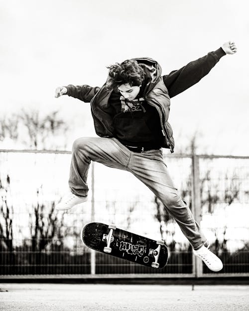 Black and White Shot of a Man Doing Skateboard Trick