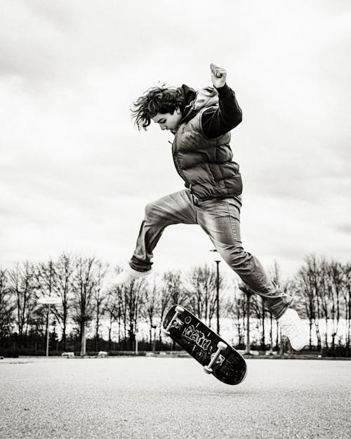 Black and White Photo of Man Doing a Skateboard Trick