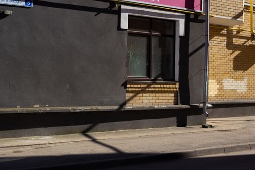 Street view of a brick and concrete building facade with window and shadow patterns.