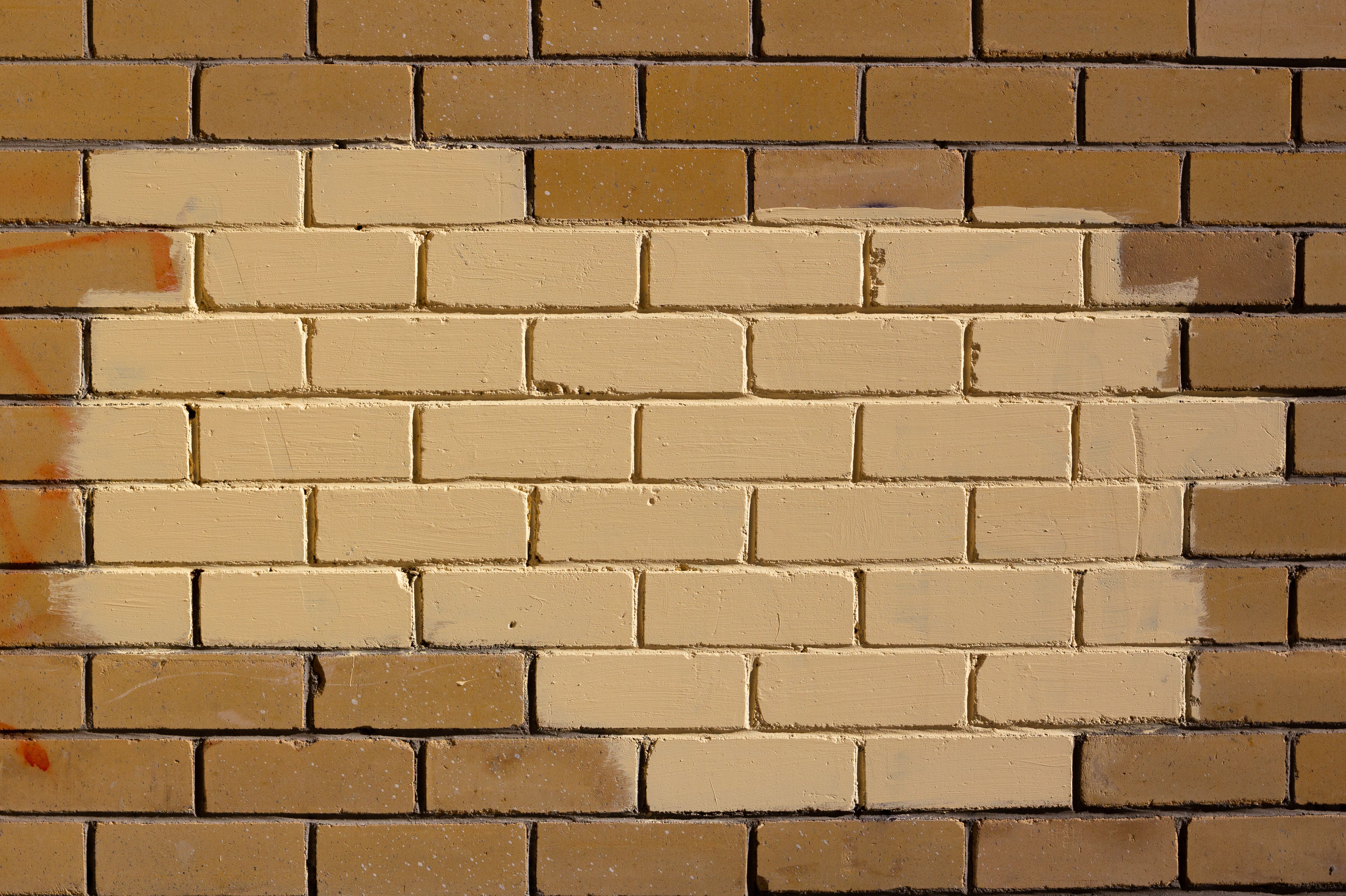 Close-up of painted yellow brick wall with distinct patterns and textures.