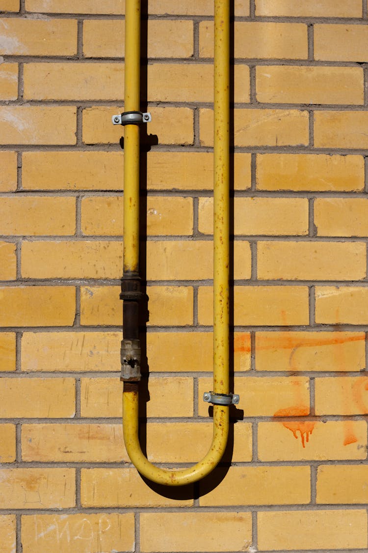 Yellow Pipe On Brick Wall