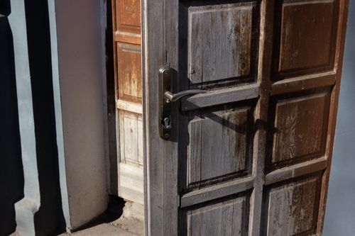 Free Weathered wooden door slightly ajar, showcasing vintage design and natural texture. Stock Photo