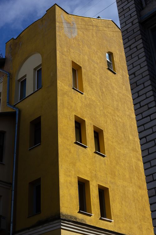 Free A striking yellow building showcasing modern architectural design with windows against a clear sky. Stock Photo