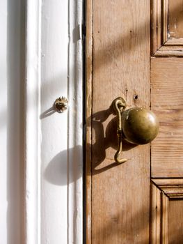 Close-up of an antique brass doorknob on a rustic wooden door, evoking a vintage feel.