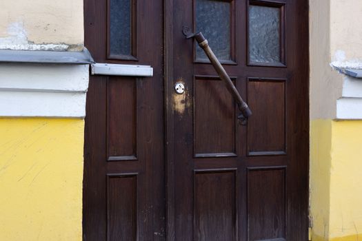 Close-up of a wooden door with a distinct handle and colorful facade in an urban environment.