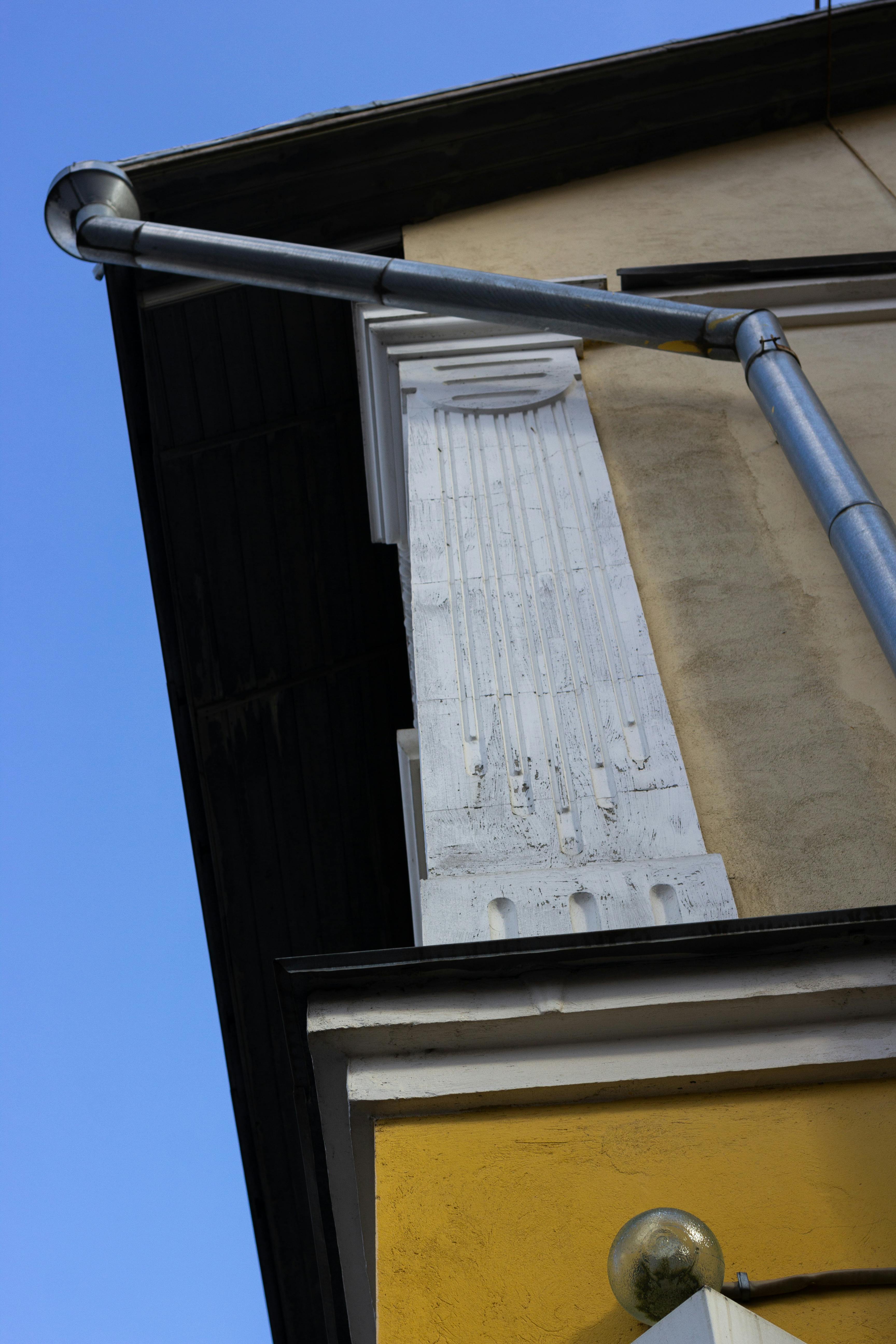 Free A low angle shot displaying the exterior of a building with visible pipes and architectural details. Stock Photo