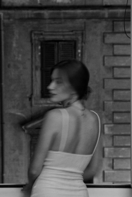 Black and white photo of a woman in Rome, showcasing classic architecture.