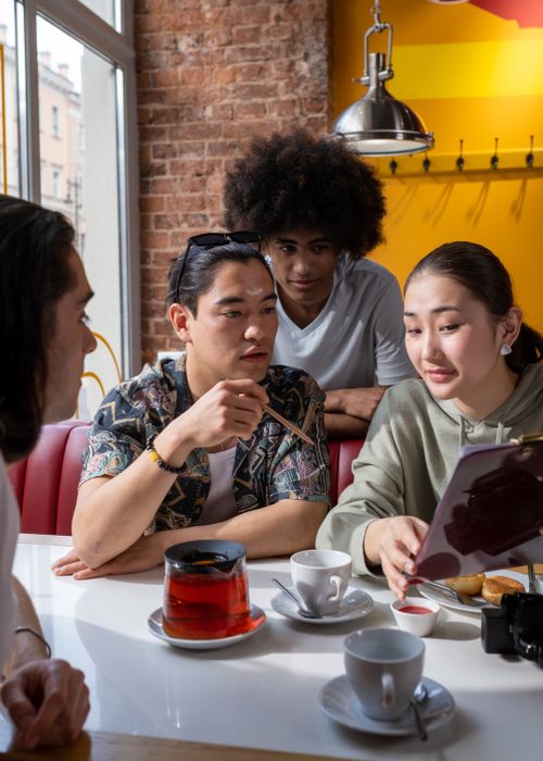 Free Group of diverse adults discussing over coffee and tea in a modern cafe setting. Stock Photo