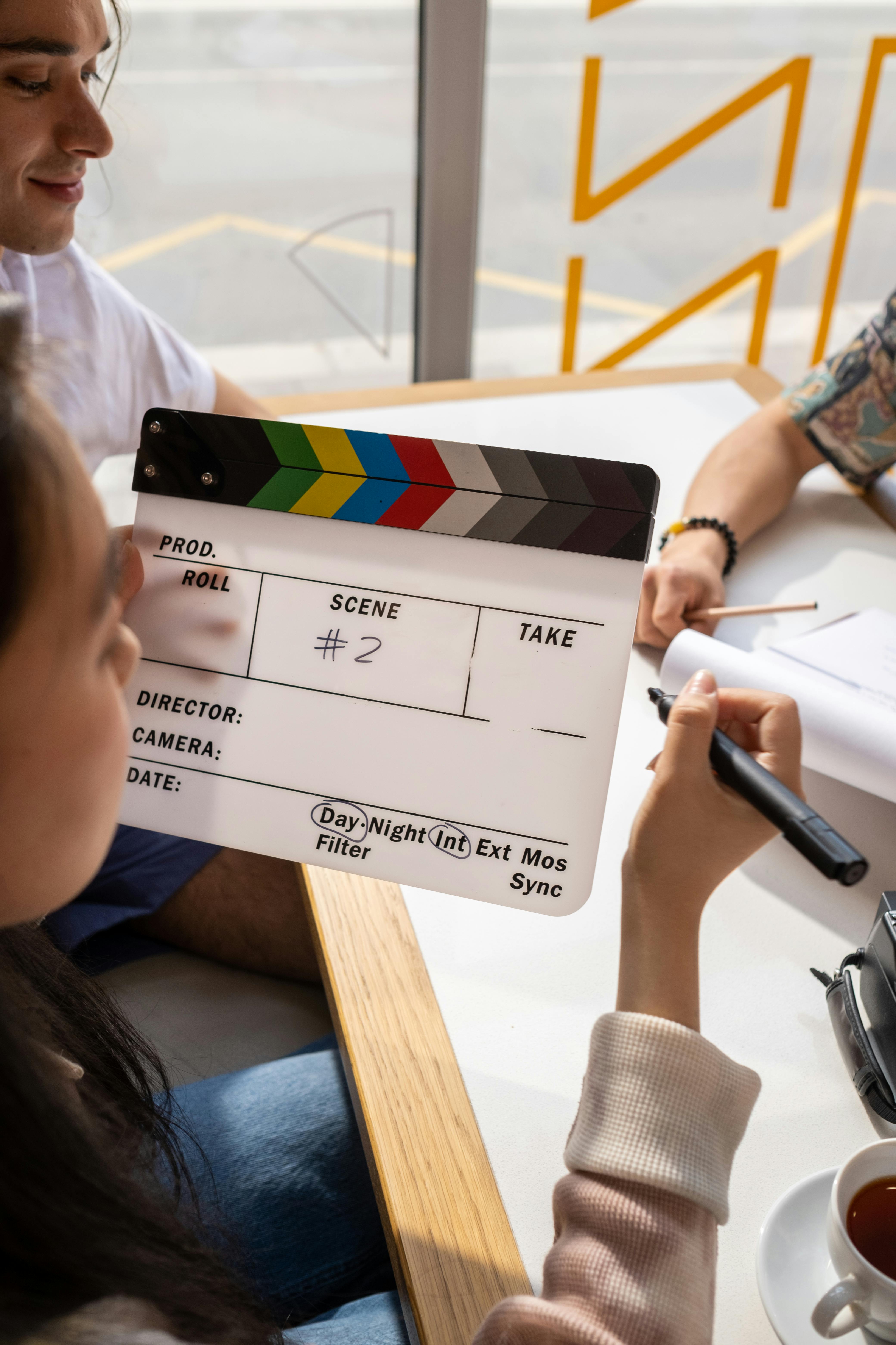 young adults sitting together in a cafe, holding scripts and talking intensely.