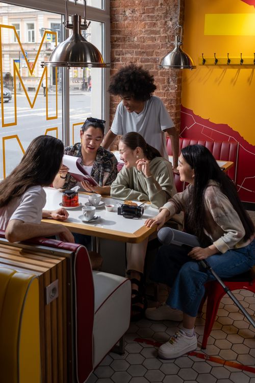 Free Group of young adults enjoying coffee and conversation in a lively, modern café setting. Stock Photo