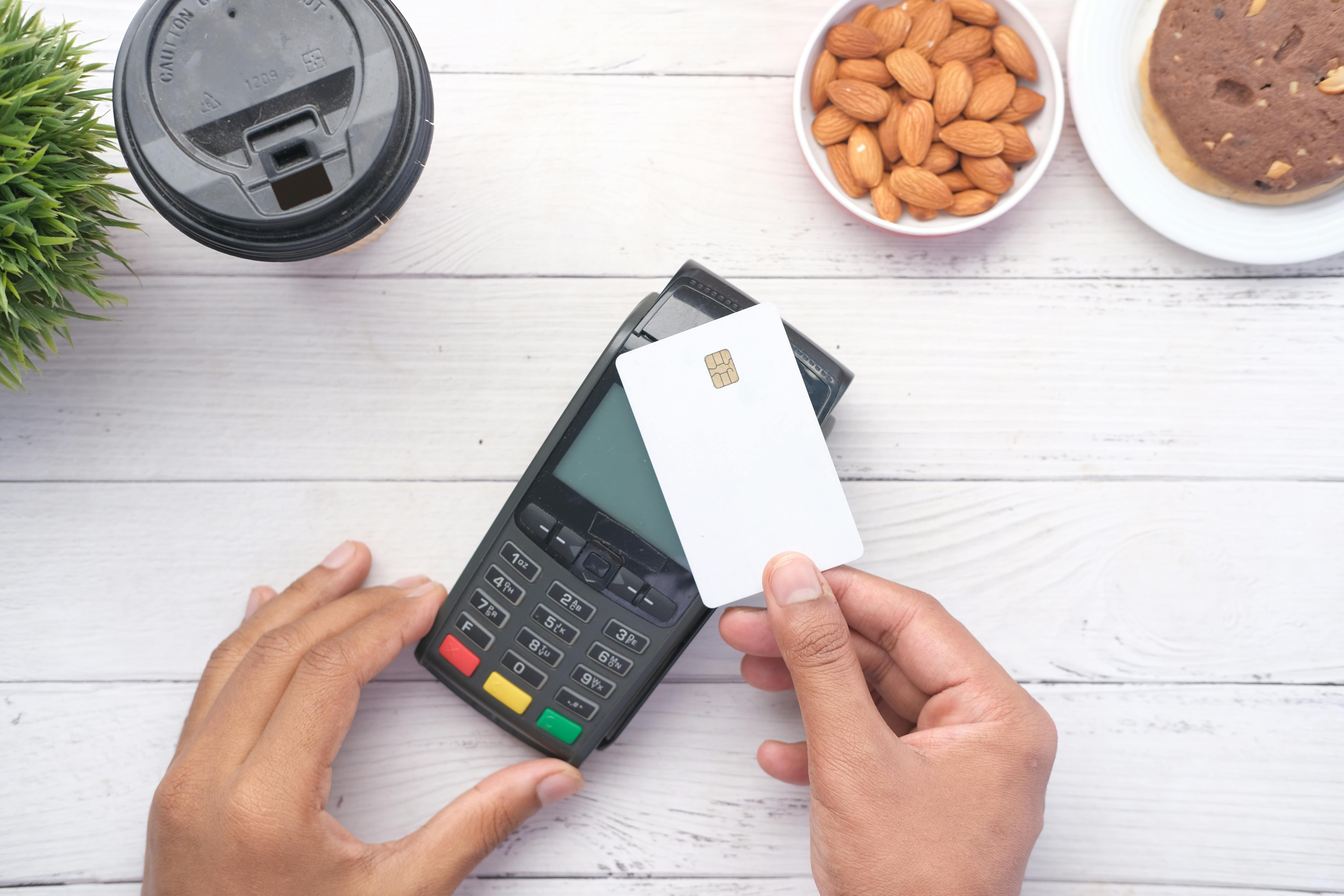 person holding credit card and payment terminal