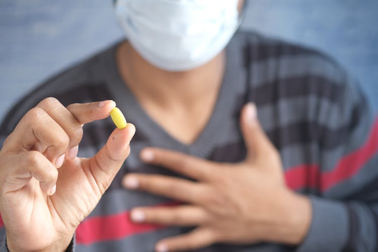 Person Holding A Yellow Pill