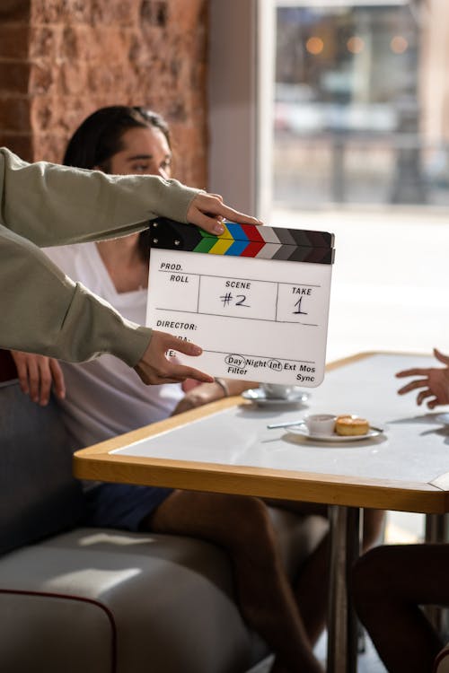 An amateur crew member holding a clapperboard in front of actors