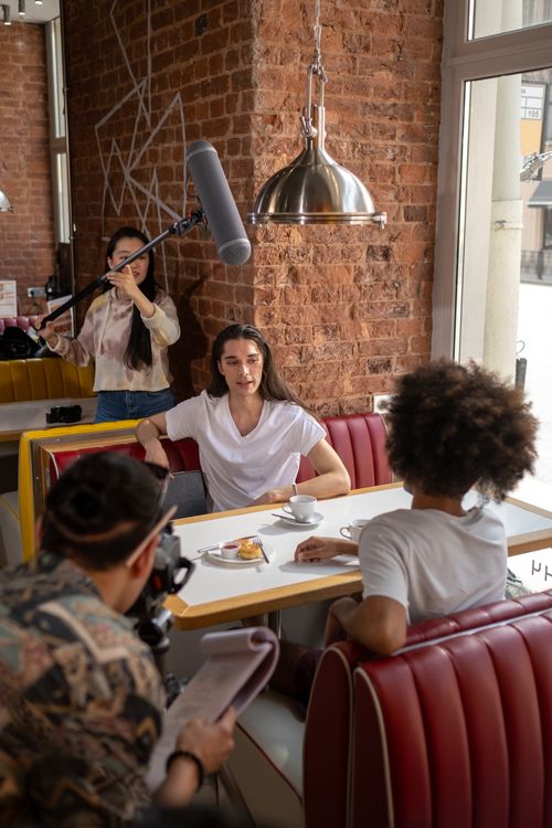 Free A candid interview setup in a stylish cafe, featuring a diverse group of young adults. Stock Photo