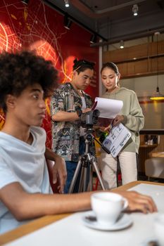 Film crew collaborating on a project in a café setting. Engaged in discussion and setup.