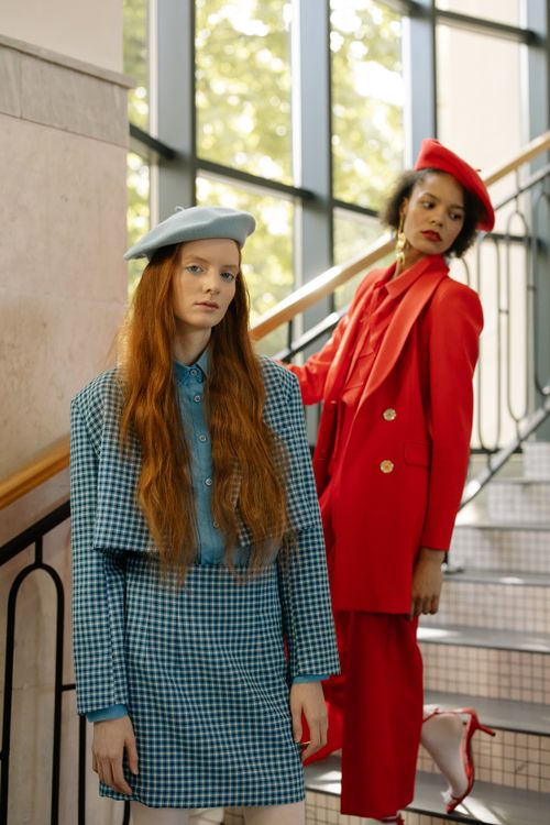 Free Two fashion models in colorful outfits posing stylishly indoors on a staircase. Stock Photo
