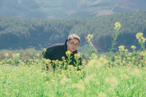 Man in Black Pullover Hoodie Standing in Flower Field