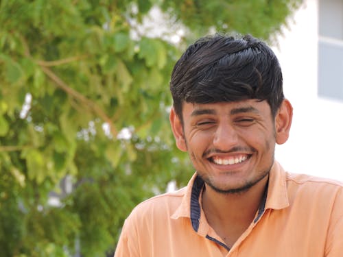 Man Smiles While Taking Photo Near Tall Tree at Daytime