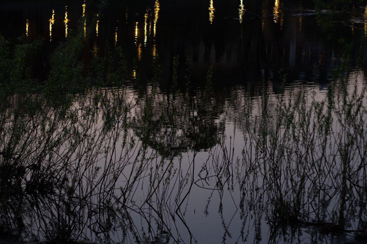 serene view of shimmering lights reflecting on a lake during dusk surr
