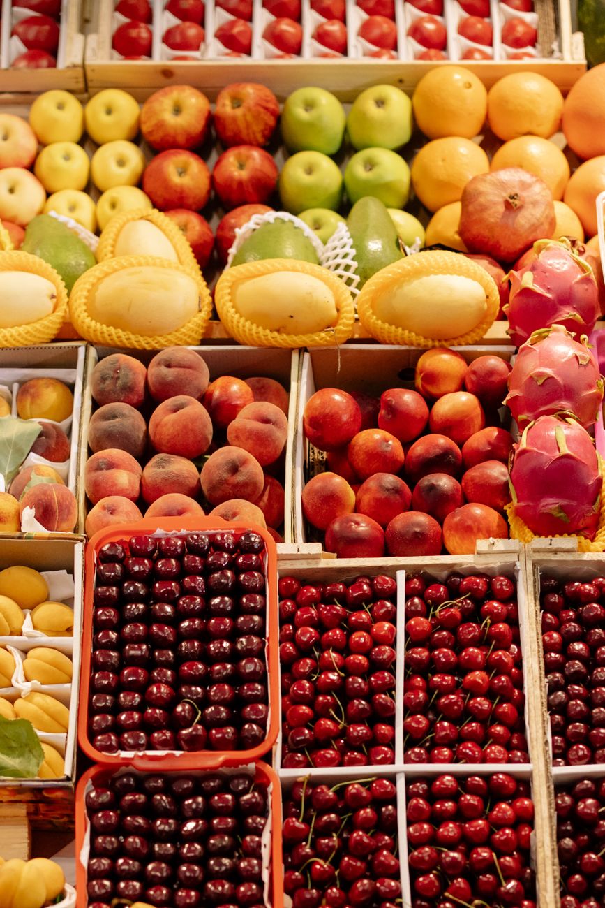A colorful assortment of fresh fruits including cherries, apples, and dragon fruit at a marketplace