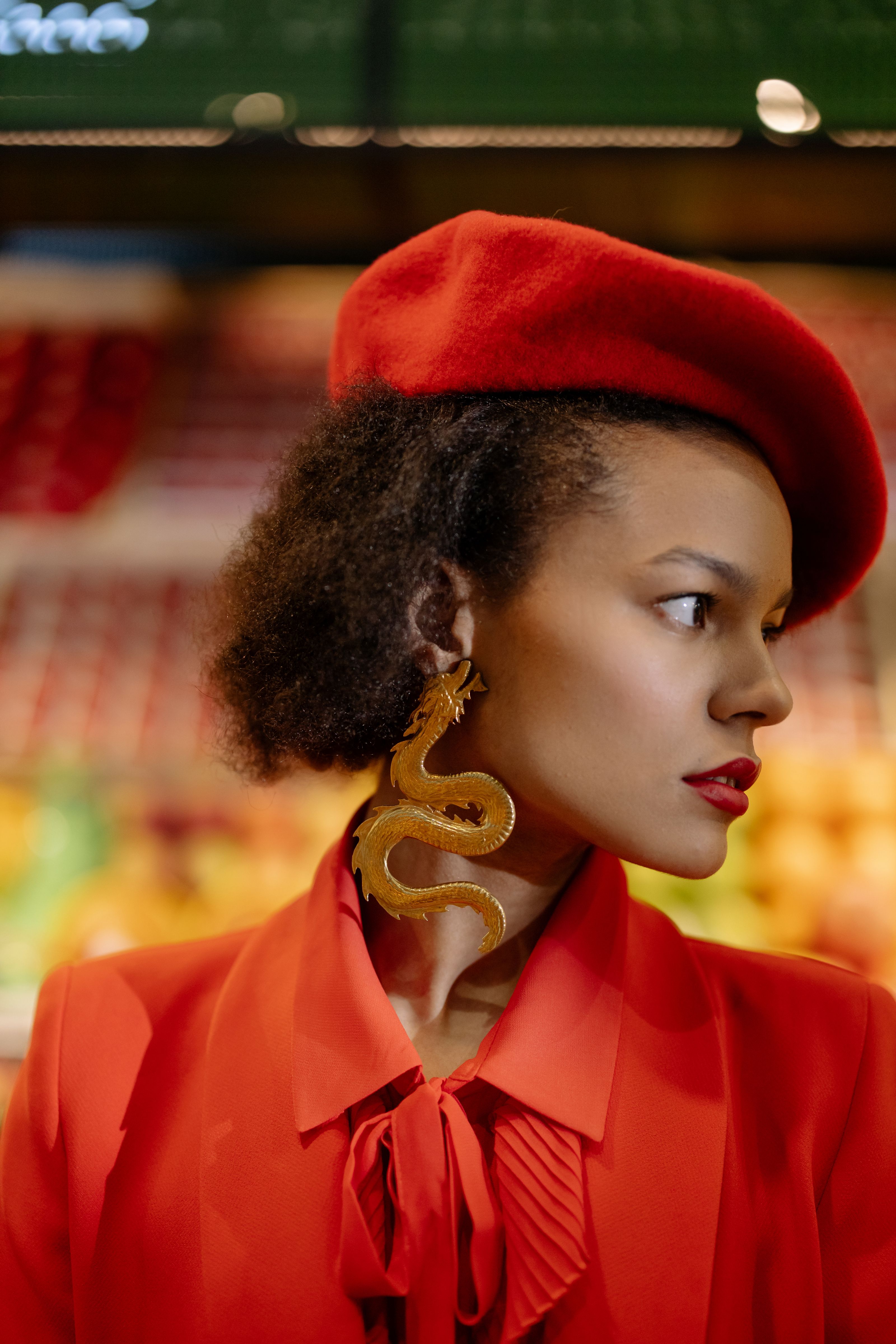 Retrato de close de uma mulher estilosa usando uma boina vermelha e brincos ousados. Pose à frente da moda e séria.