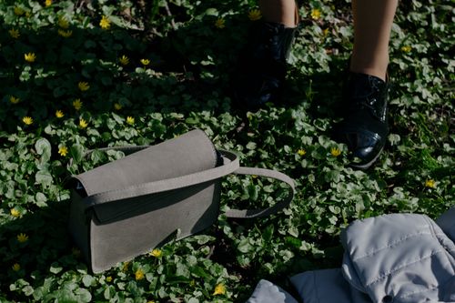 Free Fashion scene with a gray handbag on green grass surrounded by yellow flowers and black shoes. Stock Photo