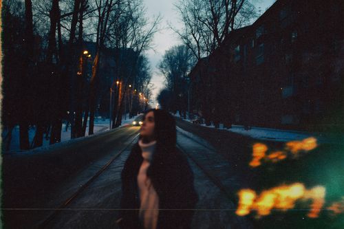 Free A blurred image of a woman on a snowy, dimly lit urban street at dawn. Stock Photo