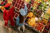 Woman in Blue Denim Jacket and White Pants Carrying a Basket of Fruits