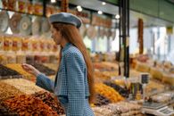 Woman in Blue and White Checkered Dress Shirt Standing in Front of Fruit Stand