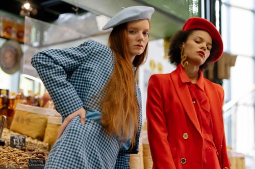 Free Two stylish women in blazers and berets posing elegantly in a market. Stock Photo