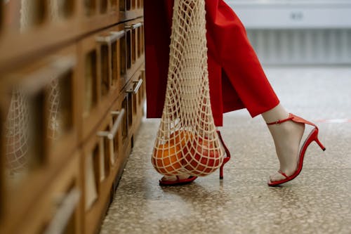 A Person Holding Mesh Bag with Fruits Inside