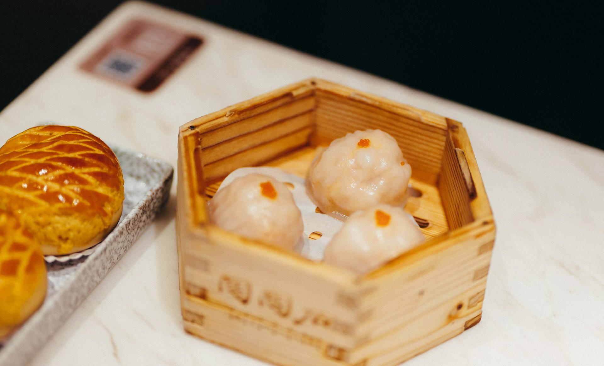 Close-up of dim sum in a bamboo steamer with pastry, capturing a delicious moment.